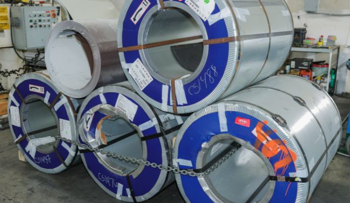 A group of rolls of steel with blue tape on them.