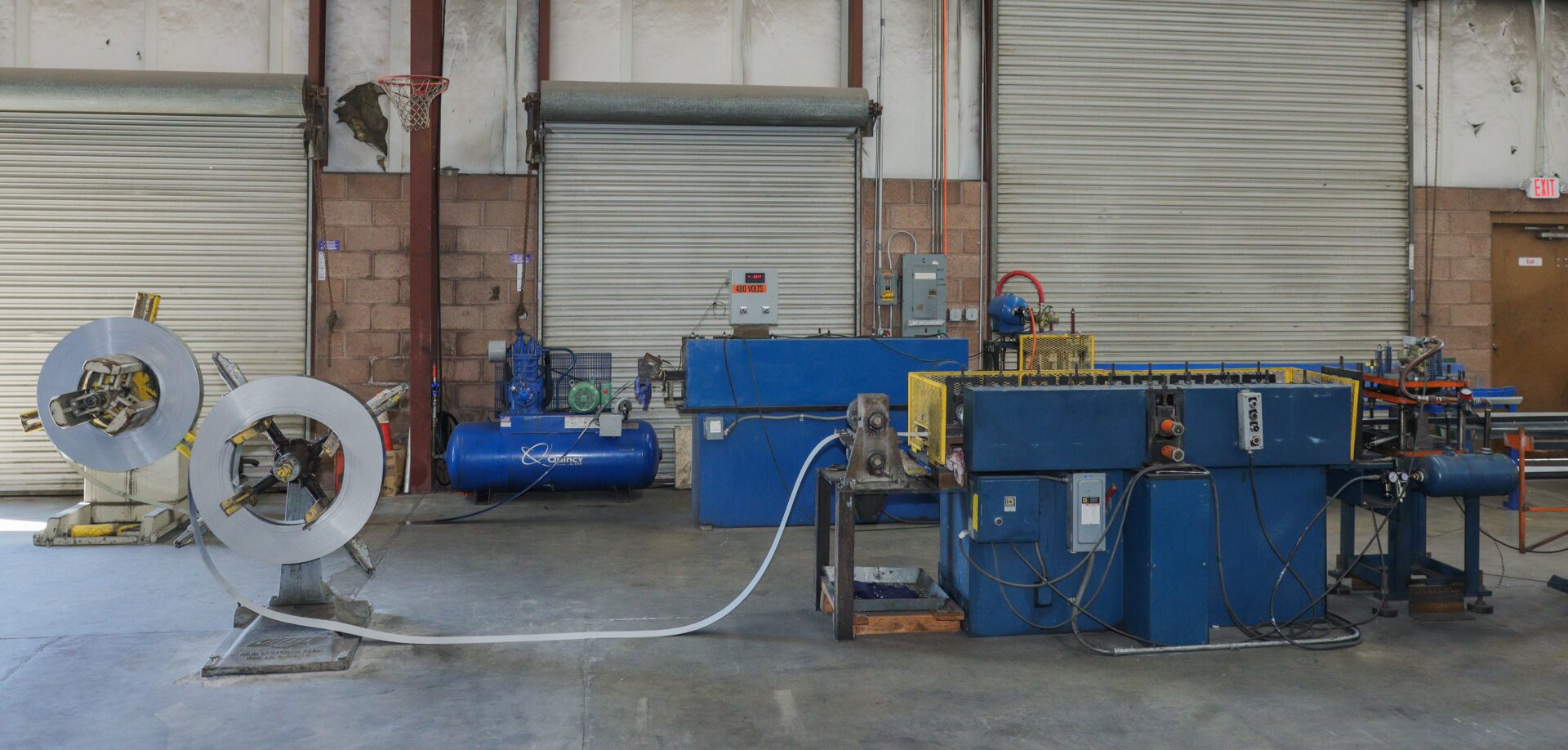 A blue machine in an industrial setting with pipes.