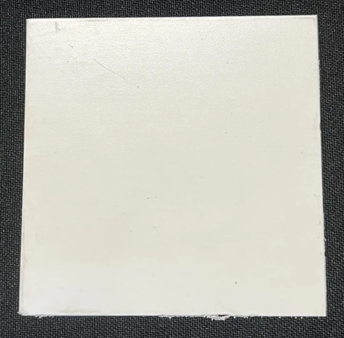 A white tile with black border on the ground.